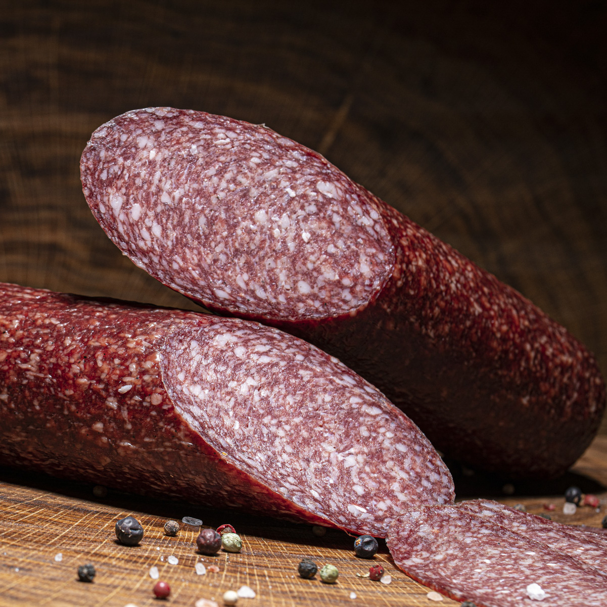 Hauseigene Salami groß aufgeschnitten auf einem Holztisch.