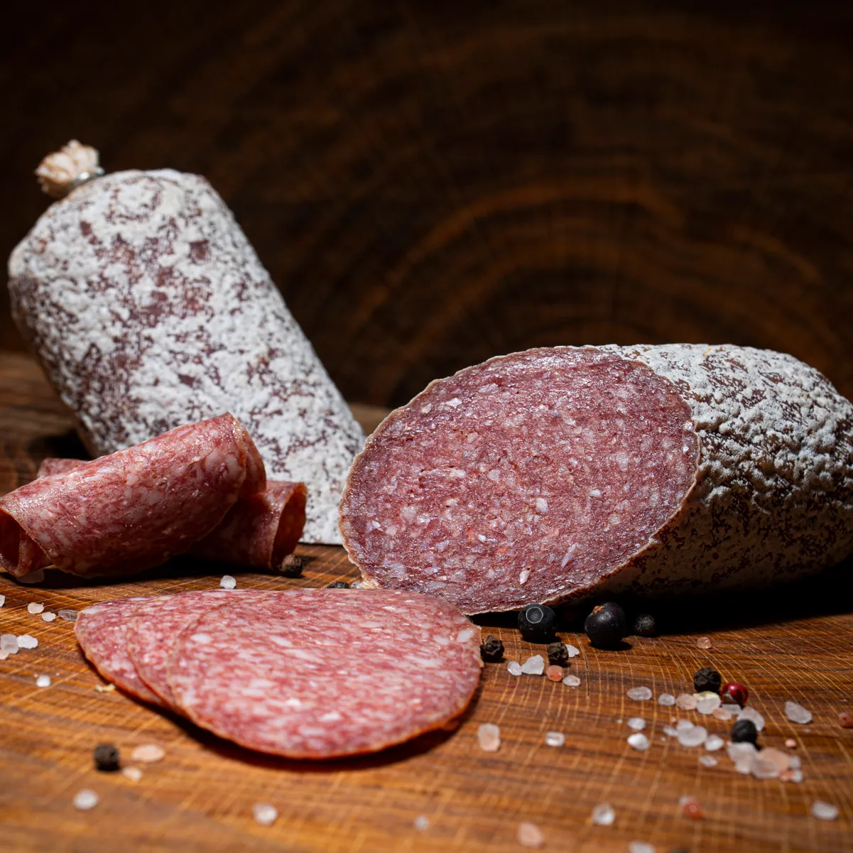 Mangalitzasalami in klein, aufgeschnitten auf einem Holzbrett.