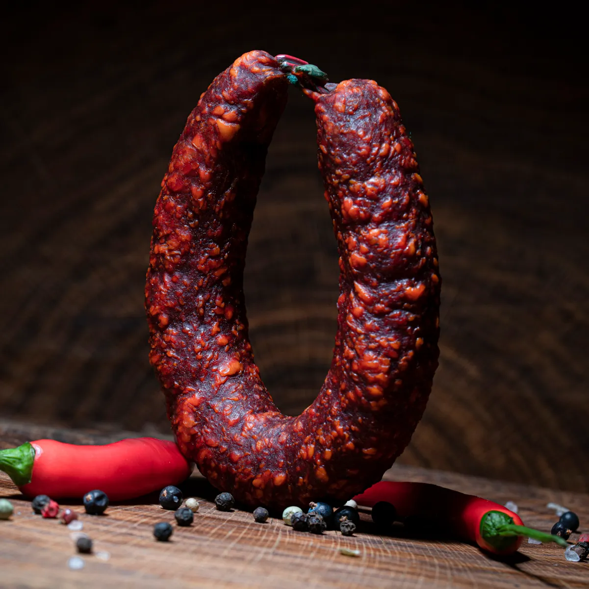 Extra scharfe Höllenwurst mit Deko-Chili auf Tischplatte.