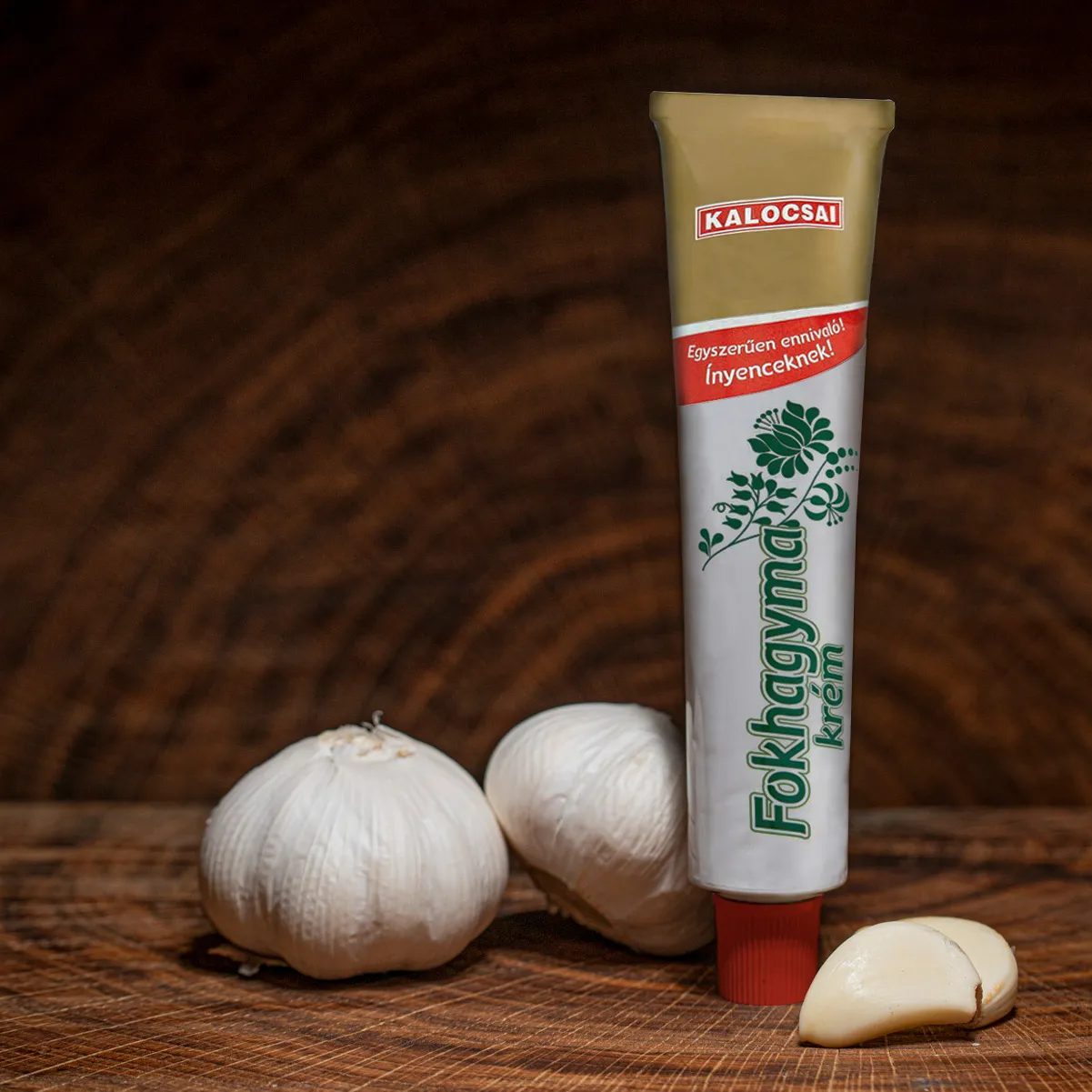 Kalocsai ungarische Knoblauchcreme Tube mit Knoblauchknollen auf Holzbrett.