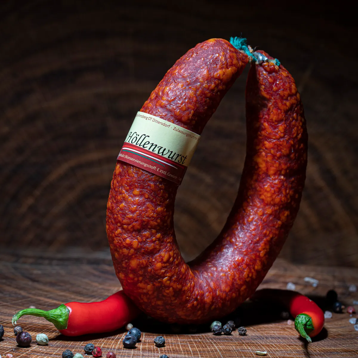 Scharfe Höllenwurst mit Deko-Chili auf Tischplatte.